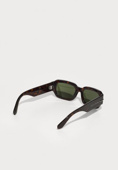 Tortoiseshell sunglasses with green lenses, angular frame design, and glossy finish. Features brand logo on the side and textured temples.