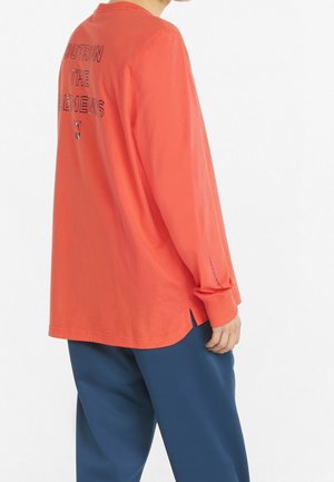 Chemise à manches longues couleur corail avec un graphique imprimé "OUTRUN THE ELEMENTS" au dos, avec une fente sur le côté et des poignets côtelés.