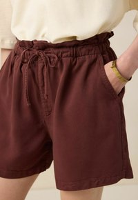 Shorts en coton bordeaux avec taille élastique et cordon de serrage, dotés de poches latérales et d'une texture lisse et légère.