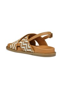 Sandalias deslizables trenzadas en color marrón claro y blanco, que cuentan con una suela baja y contorneada y una correa ajustable para el tobillo con acentos de herrajes dorados.