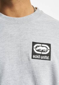 Šedá mikina s kulatým výstřihem vyrobená z bavlny s žebrovaným límcem. Má černou vyšívanou nášivku s designem nosorožce.