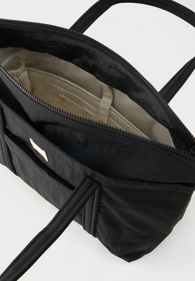 Μαύρη γυναικεία τσάντα με διπλές λαβές, ανοιχτό φερμουάρ στην κορυφή, μπεζ εσωτερικό με τσέπη με φερμουάρ και ιμάντα με κούμπωμα κλικ.