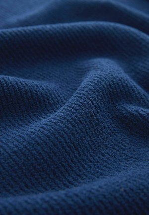 Sötétkék textília, texturált, bordázott felülettel, amely lágy, szőtt szálakat és finom árnyalatbeli eltéréseket mutat.