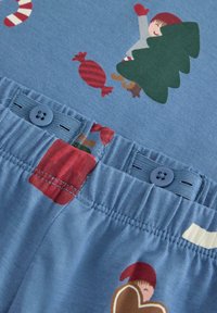 Blue pajama fabric featuring a playful pattern of gingerbread men, candy, and a tree. Waistband includes a button and elastic for adjustment.