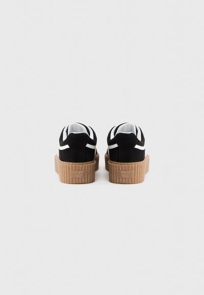 Μαύρα σουέντ sneakers με πλατφόρμα και λευκές λεπτομέρειες, καφέ λαστιχένια σόλα με υφή και στρογγυλεμένη μύτη. Η πίσω όψη δείχνει διπλό σχέδιο με μαύρες και λευκές ρίγες.