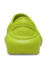 Grüne Gummi-Clogs mit einer strukturierten, gepunkteten Oberfläche und rundem Absatz. Der Markenname "crocs" ist auf der Rückseite eingeprägt.
