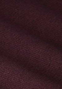 Nahaufnahme eines strukturierten Gewebes in tiefem Burgunderrot mit einem weichen, gewebten Muster.