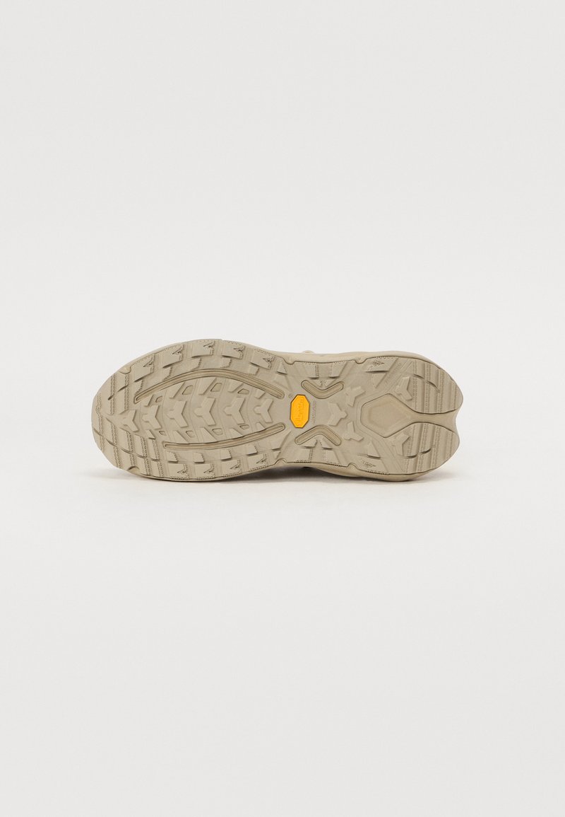 Beżowa gumowa podeszwa buta z głębokim wzorem bieżnika. Posiada żółte logo Vibram, co oznacza trwałą przyczepność na różnych powierzchniach.