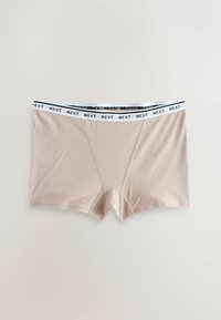 Boxers beige avec ceinture élastique blanche comportant le texte noir répété « NEXT », affichés à plat sur un fond gris clair.