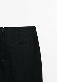 Jupe en denim noir avec une fermeture éclair dissimulée à l'arrière et un détail de poche horizontale unique. Texture lisse et design structuré.
