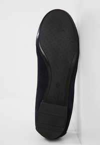 Semelle d'une chaussure plate noire avec grip texturé, nom de la marque, taille 37 et "Made in Spain" embossé sur la semelle en caoutchouc.