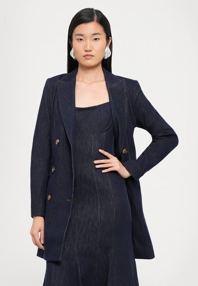 Navy denim blazer met een dubbele knoopsluiting, voorzien van gouden knopen, een geknipt kraag en een gladde structuur, gecombineerd met een bijpassende jurk.