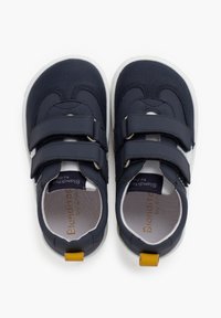 Tumedad sinised kingad kahe Velcro rihmaga, valgete tallade ja tekstuuriga pealispinnaga. Säärel on kollane aktsent.