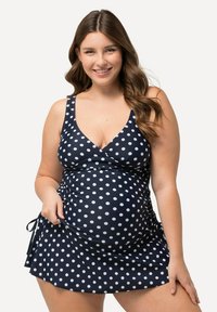 Maillot de bain bleu marine avec des pois blancs, design en V, liens latéraux ajustables, texture froncée, adapté pour les vêtements de maternité.