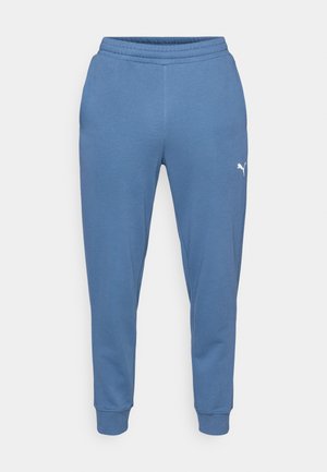 Blå sweatpants lavet af blød stof, med elastisk talje og tapered ben, forsynet med et lille hvidt logo på venstre lår.