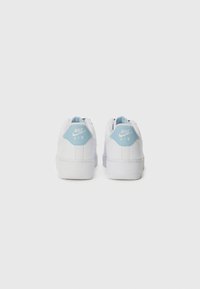 Nike Air sneakers with a white leather upper, light blue heel tab, and rubber sole. Features stitching accents and a textured outsole.