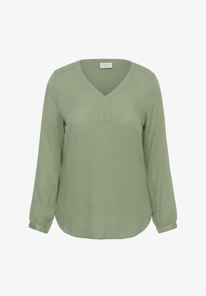 Zaļa blūze ar garām piedurknēm un V-veida izgriezumu, izgatavota no viegla, teksturēta auduma ar elastīgām aprocēm. Apaļa apakšmala.