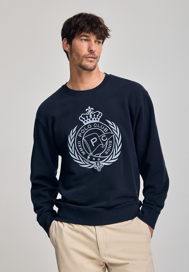 Felpa blu navy con scollo tondo e maniche lunghe, caratterizzata da un design del logo bianco con una corona e accenti di alloro sul davanti.