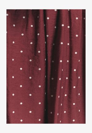 Burgundy-kangasta, jossa on texturoitu pinta ja tasaisesti sijoitettuja valkoisia pilkkuja, luoden yksinkertaisen mutta erottuvan kuosin.