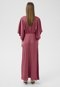 Langes, fließendes Kleid aus burgunderrotem Satin mit weiten Ärmeln und gerafftem Taillenbereich, mit einem geraden Saum, der bis zu den Knöcheln reicht.