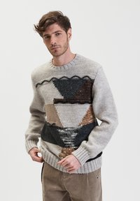 Maglione lavorato a maglia con motivi geometrici in marrone, grigio e beige; scollo rotondo, filati texturizzati e polsini e orlo a costine.