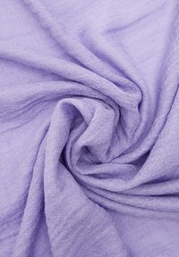 Miękka, lekka tkanina w lawendowym kolorze o subtelnej fakturze, ułożona w spiralę, ukazująca swoje delikatne, przewiewne właściwości.