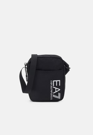 Czarna torba na ramię z regulowanym paskiem, przednią kieszenią i białym logo Emporio Armani EA7 nadrukowanym pionowo.
