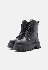 Μαύρες χειμωνιάτικες μπότες με κορδόνια, με επενδυμένες πλευρές, παχιές ανθεκτικές σόλες και λεπτομέρεια φερμουάρ στην εσωτερική πλευρά του αστραγάλου.