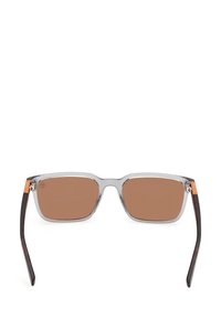 Selkeät, suorakulmaiset aurinkolasit ruskeilla linsseillä, muovikehyksillä ja tummilla kilpikonnakuosisilla varsilla. Ominaisuuksina pieni oranssi logo vasemmassa tempurissa.