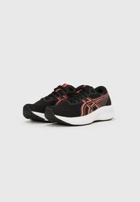 Svarte treningssko med et teksturert mesh-overlegg, med røde detaljer og en hvit mellomsåle. Yttersålen har et mønstret grep for god friksjon.