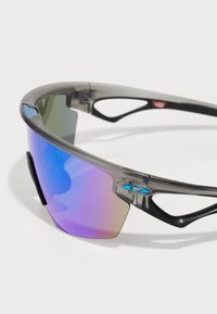 Sport-Sonnenbrille mit einem grauen Rahmen und verspiegelten Gläsern, die einen Farbverlauf von Lila und Grün zeigen. Hochkontrastierende schwarze Akzente an den Bügeln.