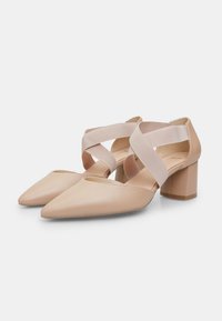 Beige leather block-heeled shoes with a pointed toe, featuring crisscross elastic straps. Smooth texture and sleek design.