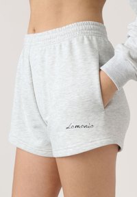 Svetlosivé bavlnené šortky s elastickým pásom, bočnými vreckami a vyšitým logom "Lamonio" na nohavici. Mäkký, ležérny dizajn.