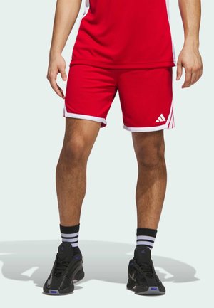 Røde sports shorts med hvid kant, prydet med et Adidas-logo på den nederste side, parret med sorte sko og sort-hvide stribede sokker.