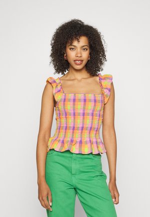 Top de xadrez multicolorido com alças franzidas e barra peplum. Tecido leve com uma textura criada por franzidos. Combinado com calças verdes.
