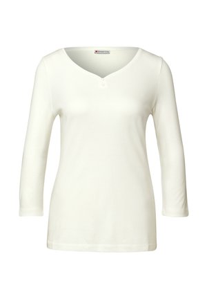 Haut blanc à manches longues avec un décolleté en V et un plastron à trois boutons. Texture lisse et coupe ajustée, fabriqué en tissu stretch doux.