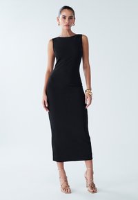 Black sleeveless midi dress with a fitted silhouette, smooth texture, and a round neckline. Worn with gold strappy heels and jewelry.