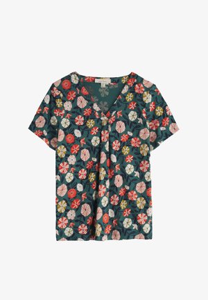 Ziedota blūze ar īsām piedurknēm, V veida kakla izgriezumu un tīrkīza krāsas fona. Ir sarkani, balti un dzelteni ziedi ar zaļām lapām. Viegls audums.