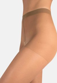 Acercamiento de una persona que lleva pantyhose beige transparentes, mostrando la cintura, la cadera y la parte superior del muslo contra un fondo claro.