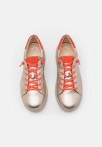 Metallicgoldene Sneakers mit orangen Schnürsenkeln und Akzenten. Glattes Lederoberteil, runde Zehenform und gepolsterter Kragen für mehr Komfort.
