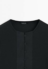Svart ribbad långärmad topp med rund halsringning och fem knappar fram, med etiketten Massimo Dutti, tillverkad i Portugal.