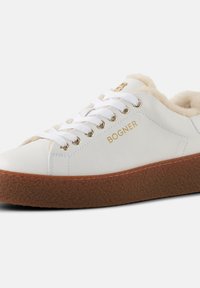 Witte leren sneaker met een bruine gestructureerde zool, gouden oogjes en een geakorst "BOGNER" logo. Gevoerd met zacht beige materiaal voor comfort.
