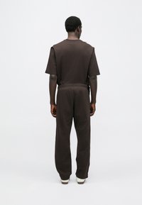 Barna rövid ujjú pamut póló hozzáillő, laza szabású nadrággal. Sima textúra, elasztikus derékpánt és minimalista design.