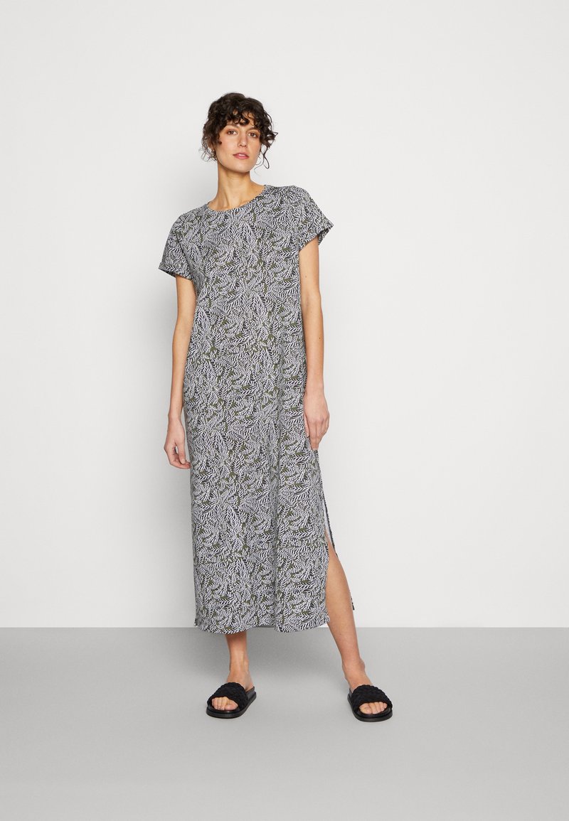 Vestido maxi com padrão de folhas em preto e branco com detalhes em verde, mangas curtas, fendas laterais e uma silhueta relaxada e reta.