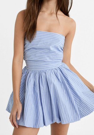 Mujer con vestido sin tirantes de rayas verticales azul y blanco, con corpiño ajustado y falda acampanada.