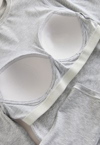 Conjunto de sujetador deportivo y leggings de tela gris acanalada, extendidos, mostrando copas acolchadas suaves y banda elástica en el sujetador.