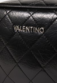 Černá prošívaná kožená taška s vystouplým stříbrným logem "VALENTINO", zvýrazněným prošíváním a texturovaným povrchem.