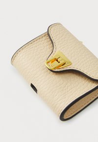Beidzītas tekstūras ādas maks ar melniem akcentiem. Aprīkots ar zelta krāsas aizdari un izliekumu, tā izmēri ir aptuveni 10 cm x 7,5 cm.
