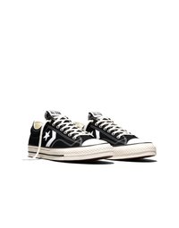 Paar schwarze Converse All Star niedrig geschnittene Sneakers mit weißen Schnürsenkeln, Sternlogo und weißen Gummisohlen auf weißem Hintergrund.