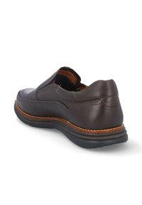 Zapato marrón de cuero tipo slip-on con paneles laterales elásticos, plantilla acolchada y suela de goma que presenta costuras en contraste y una textura suave.